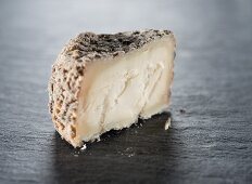 A slice of goat's cheese on a slate surface