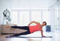 Frau macht Fitnessübung auf Yogamatte im Wohnzimmer