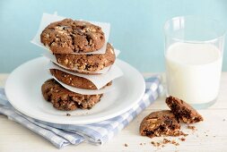 A stack of homemade hazelnut and chocolate cookies with a glass of milk