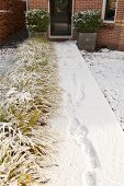 Footprints on snowy path leading to front door