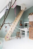 Feminine attic room with wooden ladder and white dressing table against pastel green wall