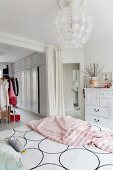 Bed linen with graphic pattern and pink blanket on feminine bed and spherical pendant lamp in bedroom