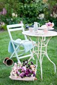 Wooden crate of violas next to vintage garden table and chair