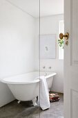 Free-standing, vintage-style bathtub on concrete floor in white bathroom