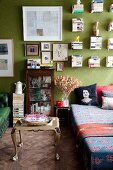 Barocker Couchtisch neben Tagesbett im Wohnzimmer mit grüner Wand und Bücherstapeln