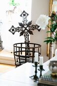 Delicate wrought iron cross in metal basket