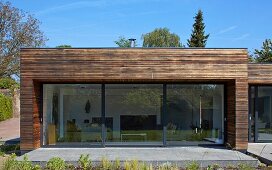 Blick von Garten auf zeitgenössisches Wohnhaus mit Terrasse und grossformatigen Glas Schiebetüren