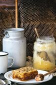 Honigwabe mit Honiglöffel und ein Glas alter Honig auf Holztisch