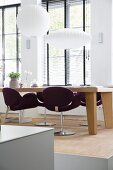 Purple swivel chairs at solid-wood dining table below white pendant lamps in front of lattice windows with louvre blinds