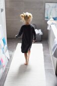 Kleines Mädchen im Bad auf weißem Teppichläufer