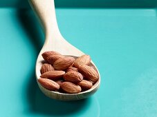 Unshelled almonds on a wooden spoon