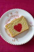 Ein Stück Biskuitkuchen mit rotem Herz zum Valentinstag