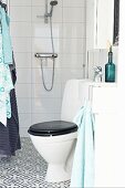 Toilette mit schwarzer Toilettengarnitur in modernem Bad, Fliesenboden mit schwarz weißem Ornament Muster