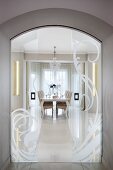 View of elegant dining area through arched doorway with open frosted glass sliding doors
