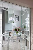 View of dining area with Ghost chairs through half-open glass sliding doors with frosted pattern