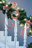 Stair balustrade decorated with fir branches and tartan ribbons