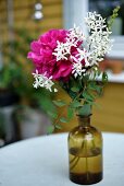 Summer flowers in apothecary bottle on garden table