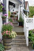 Flowering plants in wooden planter at foot of steps leading to veranda with white, wooden balustrade