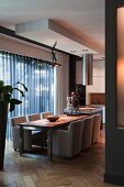 View of dining area with armchairs around table and large window with transparent curtains in open-plan interior