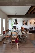 Cantilever and retro swivel chairs at long dining table below industrial-style pendant lamps in open-plan, loft-apartment interior