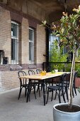 Wooden table and bistro chairs next to restored brick façade of loft apartment