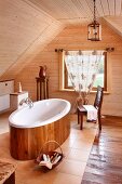 Freistehende Badewanne mit Holzeinkleidung auf gefliestem Boden, in holzverkleidetem Dachgeschoss