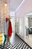 Foyer in period building with chequered, tiled floor, coat stand and view into living area