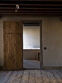 View of bathtub through open, rustic, interior door