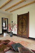 Edle Kissen mit Seidenbezug auf Tagesliege, antike marokkanische Tür und Bodenvase auf Perserteppich