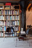 Schwarze Stühle im Retro Stil vor Bücherregal, seitlich schwarze Metallstütze in Loftwohnung