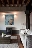 Pale grey sofa, cubic coffee table and large Renaissance portrait on wall in rustic loft apartment