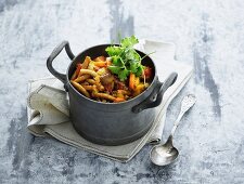 Vegetable stew with beef, mushrooms and pasta in a small pot