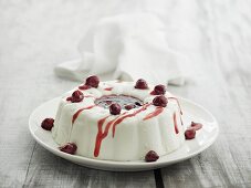A cream pudding with cherry sauce