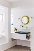 Designer bathroom with washstand integrated in niche below round, gilt-framed mirror on wall