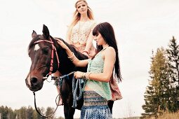 Zwei junge Frauen im Hippie-Stil mit Pferd