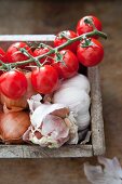 Fresh tomatoes, onions and garlic in wooden box