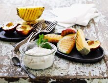 Grilled exotic fruit with a quark dip on an old table