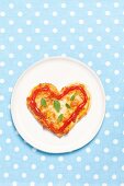 A heart-shaped mini pizza with ketchup