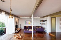 Open-plan, modern interior with exposed roof beams and purple sofa set in lounge area