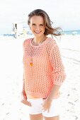 A young woman on a beach wearing an apricot coloured summer jumper