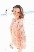 A young woman on a beach wearing an apricot coloured summer jumper