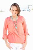 A young woman on a beach wearing a salmon pink blouse