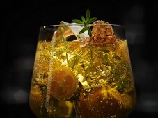 An exotic drink with honeycomb, kumquats, ice cubes and a herb garnish