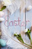 Easter arrangement of eggs, feathers, flowers & 'Easter' written in wire