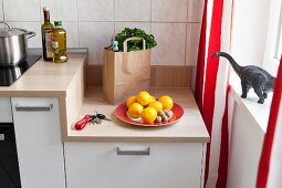 A kitchen unit with a wooden work surface next to a window with red-and-white striped curtains