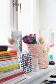 Stacked books, decorative storage box and woven basket on windowsill