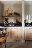 Kitchen counters with dark worksurfaces and wooden fronts separated by partition