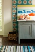 Grey-painted cabinet and magazine rack next to striped rug