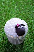 An Easter lamb cupcake on a grass surface