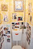 Collection of photos & pictures on tiled and papered walls in toilet